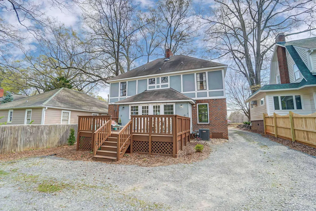 A welcoming exterior shot of a wooden deck attached to a brick building, surrounded by trees. The scene captures the relaxing atmosphere perfect for unwinding after work or casual outdoor gatherings, with soft natural lighting accentuating the space.