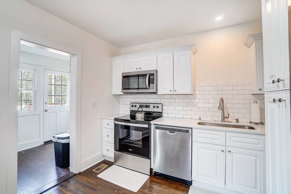 A cheerful kitchen scene with gleaming stainless steel appliances, crisp white cabinets, and a stylish subway tile backsplash. The image highlights the kitchen's fresh and inviting atmosphere, perfect for both quick breakfasts and cozy dinners.