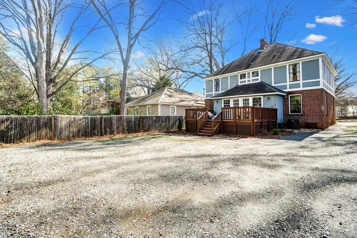 A welcoming view of the home's wooden deck surrounded by trees, with a clear view of the spacious backyard. The area is perfect for gatherings, relaxation, and outdoor play, showing the connection between home and nature.