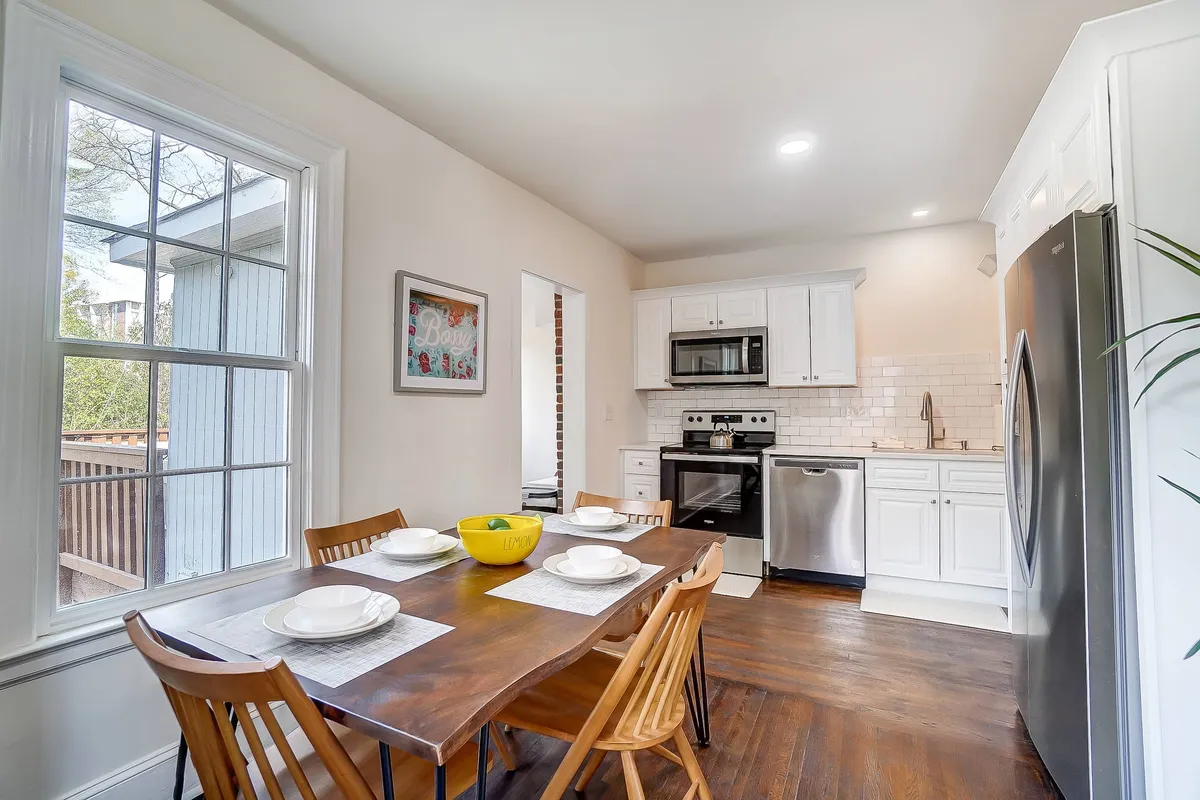 An open, airy dining area featuring a generous dining table, modern kitchen appliances, and a large window streaming with natural light. The setting is ideal for family meals, planning adventures, or casual gatherings, with a seamless transition between the living and dining spaces.